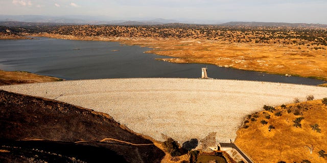 Buchanan Dam holds back water in Eastman Lake on Thursday, June 17, 2021, in unincorporated Madera County, Calif. At the time of this photo, the reservoir was at 11 percent of capacity and 20 percent of its historical average. (AP Photo/Noah Berger)