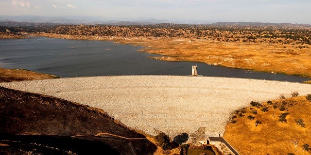 Buchanan Dam holds back water in Eastman Lake on Thursday, June 17, 2021, in unincorporated Madera County, Calif. At the time of this photo, the reservoir was at 11 percent of capacity and 20 percent of its historical average. (AP Photo/Noah Berger)