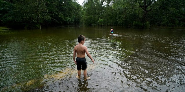 Marina Kingsmill and her brother Raylan play in the flooded street in front of their home after Tropical Storm Claudette passed through in Slidell, La., Saturday, June 19, 2021.   The National Hurricane Center declared Claudette organized enough to qualify as a named storm early Saturday, well after the storm's center of circulation had come ashore southwest of New Orleans.  (AP Photo/Gerald Herbert)