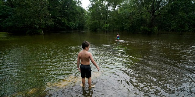 Marina Kingsmill and her brother Raylan play in the flooded street in front of their home after Tropical Storm Claudette passed through in Slidell, La., Saturday, June 19, 2021. The National Hurricane Center declared Claudette organized enough to qualify as a named storm early Saturday, well after the storm's center of circulation had come ashore southwest of New Orleans. (AP Photo/Gerald Herbert)