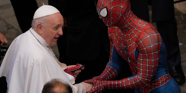 Pope Francis meets Spider-Man, who hands him his mask, after his weekly general audience with a limited number of worshipers in the San Damaso courtyard in the Vatican, Wednesday, June 23, 2021. The masked man works with the sick children in hospitals. (AP Photo / Andrew Medichini)