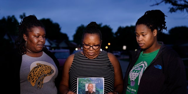 May 17, 2021: Michelle Branch, center, holds a pamphlet from the memorial service of her younger brother, Craig Elazer, 56, along with Elazer's stepdaughter, Shatia Jones, right, and niece, Alexa Sanders, in St. Louis.