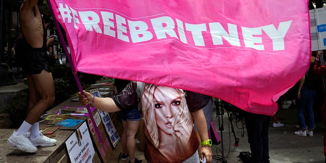 A Britney Spears supporter waves a "Free Britney" flag outside a court hearing concerning the pop singer's conservatorship at the Stanley Mosk Courthouse, Wednesday, June 23, 2021, in Los Angeles.