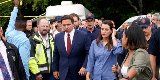 Florida Gov. Ron DeSantis, center left, and Lt. Gov. Jeanette Nunez, center right, arrive for a news conference near the scene where a wing of a 12-story beachfront condo building collapsed, Thursday, June 24, 2021, in the Surfside area of Miami. (AP Photo/Lynne Sladky)