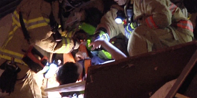This photo taken from video provided by ReliableNewsMedia, a firefighter fist bumps a survivor, after being pulled from the rubble of the Champlain Towers South Condo after the multistory building partially collapsed in Surfside, Fla., early Thursday. (ReliableNewsMedia via AP)
