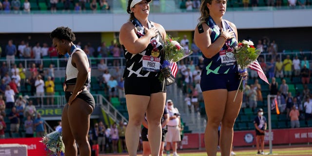 Gwendolyn Berry, left, looks away as DeAnna Price and Brooke Andersen stand for the national anthem after the finals of the women's hammer throw at the U.S. Olympic Track and Field Trials Saturday, June 26, 2021, in Eugene, Ore. Price won, Andersen was second and Berry finished third. (AP Photo/Charlie Riedel)