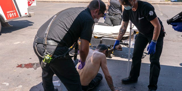 Salem Fire Department Capt. Matt Brozovich, left, and Falck Northwest ambulance personnel help treat a man experiencing heat exposure at a cooling center during a heat wave, Saturday, June 26, 2021, in Salem, Ore. (AP Photo/Nathan Howard)