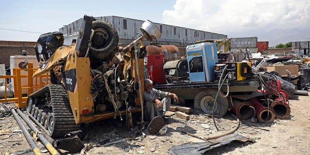 FILE - In this May 3, 2021 file photo, a man rests in the shade of destroyed machinery sold by the US military to a scrapyard, outside Bagram Air Base, in Afghanistan. In 2001 the armies of the world united behind America Bagram Air Base, barely an hours drive from the Afghan capital Kabul, was chosen as the epicenter of Operation Enduring Freedom, as the assault on the Taliban rulers was dubbed. It’s now nearly 20 years later the last US soldier is soon to depart the base. (AP Photo/Rahmat Gul, File)