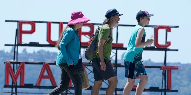 People walk near Pike Place Market, Tuesday, June 29, 2021, in Seattle. The unprecedented Northwest U.S. heat wave that slammed Seattle and Portland, Oregon, moved inland Tuesday — prompting an electrical utility in Spokane, Washington, to resume rolling blackouts amid heavy power demand.  (AP Photo/Ted S. Warren)