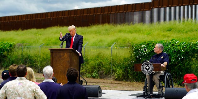 Texas Gov. Greg Abbott, right, listens to Former President Donald Trump, left, during a visit to an unfinished section of border wall, in Pharr, Texas, Wednesday, June 30, 2021. (AP Photo/Eric Gay)
