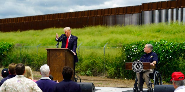 Texas Gov. Greg Abbott, right, listens to Former President Donald Trump, left, during a visit to an unfinished section of border wall, in Pharr, Texas, Wednesday, June 30, 2021.