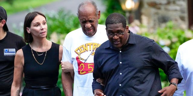 Bill Cosby, center, and spokesperson Andrew Wyatt, right, approach members of the media gathered outside Cosby's home in Elkins Park, Pa., Wednesday, June 30, 2021, after Pennsylvania's highest court overturned his sex assault conviction. 