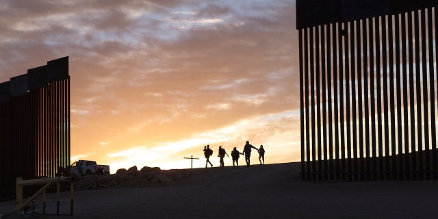 A pair of migrant families from Brazil pass through a gap in the border wall to reach the United States after crossing from Mexico in Yuma, Ariz., Thursday, June 10, 2021, to seek asylum.