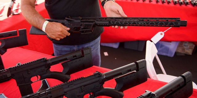 A clerk shows a customer a California legal, featureless AR-15 style rifle from TPM Arms LLC on display for sale at the company's booth at the Crossroads of the West Gun Show at the Orange County Fairgrounds on June 5, 2021 in Costa Mesa, California. (PATRICK T. FALLON/AFP via Getty Images)