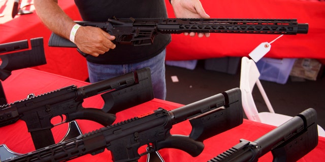 A clerk shows a customer a California legal, featureless AR-15 style rifle from TPM Arms LLC on display for sale at the company's booth at the Crossroads of the West Gun Show at the Orange County Fairgrounds on June 5, 2021 in Costa Mesa, California. (PATRICK T. FALLON/AFP via Getty Images)