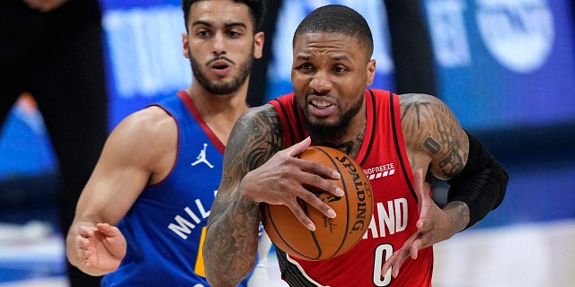 Portland Trail Blazers guard Damian Lillard (0) drives to the basket against Denver Nuggets guard Markus Howard during the second half of Game 5 of a first-round NBA playoff series, June 1, 2021, in Denver.