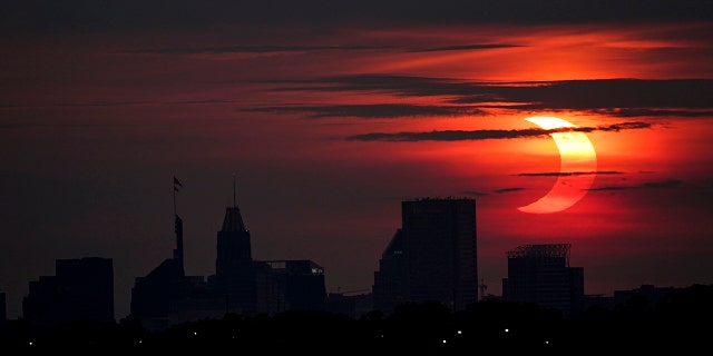 A partial solar eclipse rises over the Baltimore skyline, Thursday, June 10, 2021, seen from Arbutus, Md. (AP Photo/Julio Cortez)