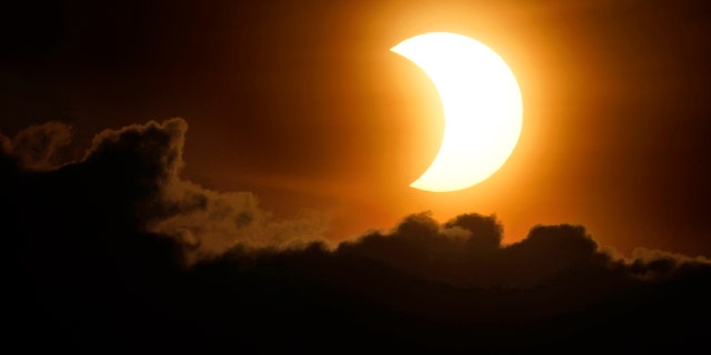 The sun is partially eclipsed as it rises over lower Manhattan in New York, Thursday, June 10, 2021. (AP Photo/Seth Wenig)