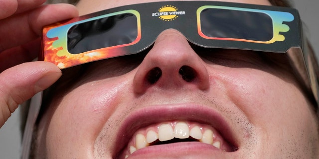 A man wears special glasses to watch the partial solar eclipse in Trafalgar Square in London, Thursday, June 10, 2021. (AP Photo/Frank Augstein)