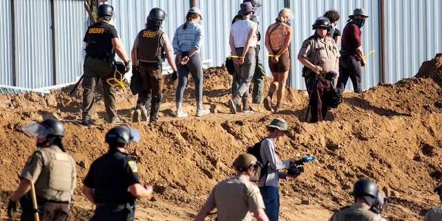 FILE - In this June 7, 2021, file photo, activists are walked through an Enbridge Line 3 pump station after being arrested near Park Rapids, Minn. Members of the Rise Coalition, an Indigenous-led environmental organization, and allies erected a prayer camp on June 7 at the Enbridge construction site along the Mississippi River near Solway. They and other Line 3 opponents had marched to the area with hundreds of others protesting the pipeline before pitching their camp at the end of a wooden boardwalk leading to the site. (Evan Frost/Minnesota Public Radio via AP, File)