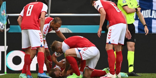 Denmark players help Denmark's midfielder Christian Eriksen after he collapsed before the medics arrive during the UEFA EURO 2020 Group B football match between Denmark and Finland at the Parken Stadium in Copenhagen on June 12, 2021. (JONATHAN NACKSTRAND/AFP via Getty Images)