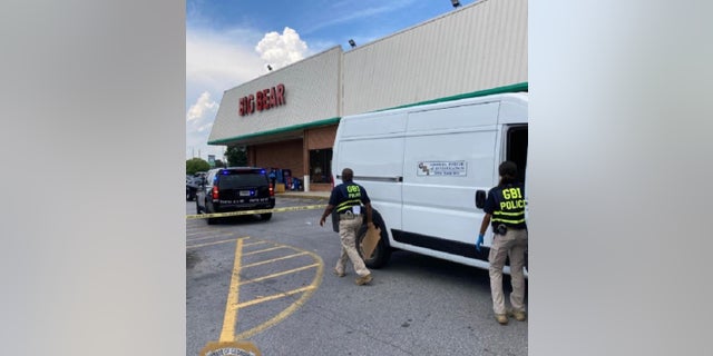 Investigadores de la Oficina de Investigaciones de Georgia en el lugar de un tiroteo en un supermercado el lunes en el que murió un cajero y el presunto pistolero y un oficial de reserva resultaron heridos.