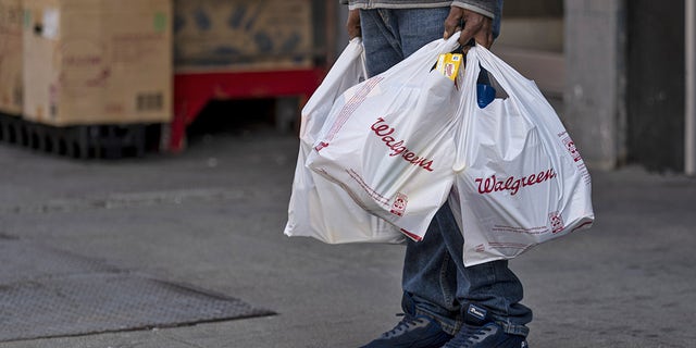 A person holds Walgreens shopping bags in front of a store in San Francisco, California, U.S., on Tuesday, April 13, 2021. Walgreens Boots Alliance Inc. is scheduled to release earnings figures on April 15.