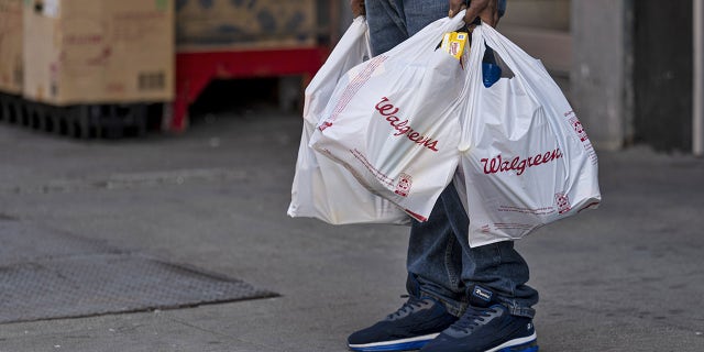 A person holds Walgreens shopping bags in front of a store in San Francisco, California, U.S., on Tuesday, April 13, 2021. Walgreens Boots Alliance Inc. is scheduled to release earnings figures on April 15.