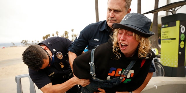 LAPD officers wrestle a knife away from a person called Angel who they arrested for assault with a deadly weapon as she stood only a few feet behind Los Angeles Mayoral candidate Joe Buscaino on Monday, June 7, 2021, in Los Angeles, CA. (Al Seib / Los Angeles Times via Getty Images).
