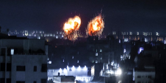 Explosions light-up the night sky above buildings in Gaza City as Israeli forces shell the Palestinian enclave, early on June 16, 2021.