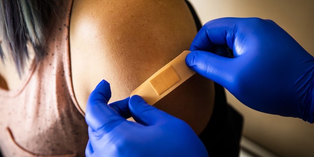 A healthcare professional places a band-aid on a patient after administering a dose of the Pfizer-BioNTech Covid-19 vaccine at Boston Medical Center in Boston, Massachusetts, U.S., on Thursday, June 17, 2021. Adam Glanzman/Bloomberg via Getty Images