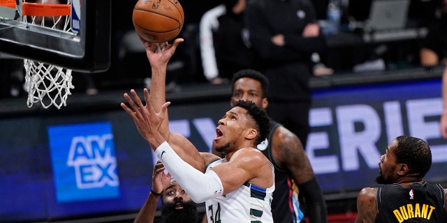Milwaukee Bucks forward Giannis Antetokounmpo (34) shoots with Brooklyn Nets guard James Harden, left, and forward Kevin Durant (7) defending during the first half of Game 5 of a second-round NBA basketball playoff series Tuesday, June 15, 2021, in New York. (AP Photo/Kathy Willens)