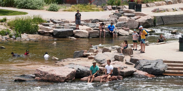 People cool off in the water at the confluence of the South Platte River and Cherry Creek in Denver, Wednesday June 16, 2021.