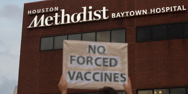 FILE - In this June 7, 2021, file photo, a person holds a sign to protest at Houston Methodist Hospital in Baytown, Texas, a policy that says hospital employees must get vaccinated against COVID-19 or lose their jobs. June 22, 2021. (Yi-Chin Lee/Houston Chronicle via AP, File)