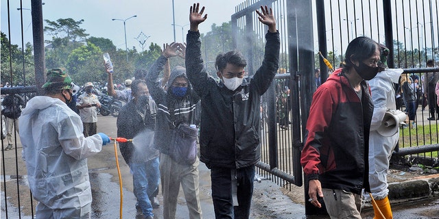 June 17, 2021: Soldiers in protective suits spray disinfectant on people entering the Gelora Bandung Lautan Api Stadium to receive the Sinovac COVID-19 vaccine during a mass vaccination in Bandung, West Java, Indonesia.