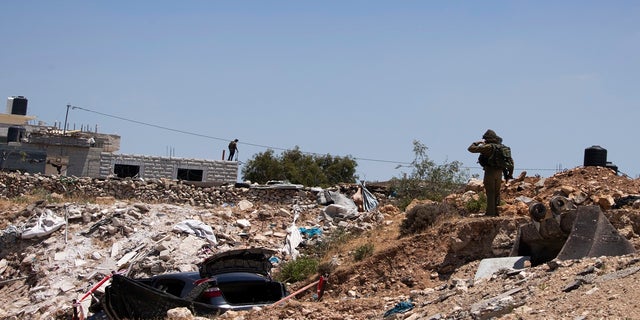 An Israeli soldier stands near a car said to be used in an attack near Hizmeh Junction in the West Bank on Wednesday. (AP)