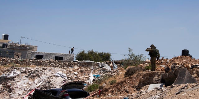 An Israeli soldier stands near a car said to be used in an attack near Hizmeh Junction in the West Bank on Wednesday. (AP)