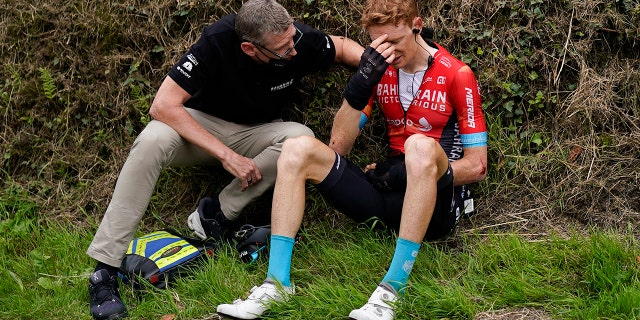 Australia's Jack Haig gets assistance from a team member after crashing during the third stage of the Tour de France cycling race over 113.65 miles with start in Lorient and finish in Pontivy, France, Monday, June 28, 2021. (AP Photo/Daniel Cole)