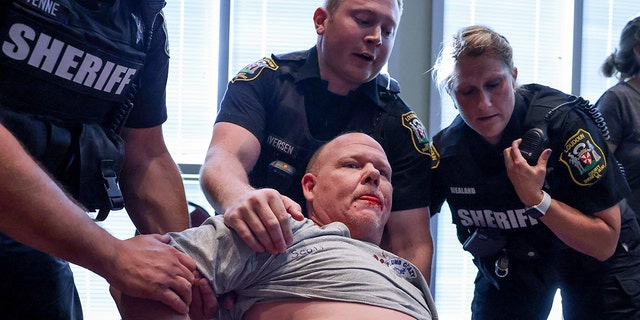 A man is being held after a fight broke out during a Loudoun County School Board meeting, which includes a discussion of Critical Race Theory and transgender students, in Ashburn, Virginia, June 22, 2021. REUTERS / Evelyn Hockstein TPX IMAGES OF THE DAY