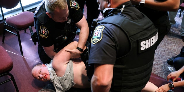 A man is detained after a fight broke out during a Loudoun County School Board meeting which included a discussion of Critical Race Theory and transgender students, in Ashburn, Virginia, on June 22, 2021.