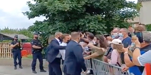 In this image taken from video, French President Emmanuel Macron, center, is slapped by Damien Tarel -- who is in a green T-shirt -- during a visit to Tain-l’Hermitage in France on Tuesday.  (BFM TV via AP)