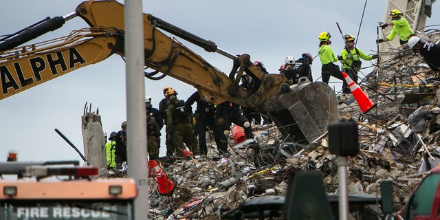 Rescue workers dig through the rubble with the aid of a backhoe at the site of the collapsed condominium in Surfside, Fla., Monday, June 28, 2021. (Jose A Iglesias/Miami Herald via AP)