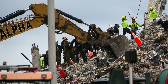 Rescue workers dig through the rubble with the aid of a backhoe at the site of the collapsed condominium in Surfside, Fla., Monday, June 28, 2021. (Jose A Iglesias/Miami Herald via AP)