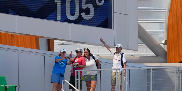 Fans pose for photos near current temperature signs at the U.S. Track and Field Olympic Games. On Sunday, June 27, 2021 in Eugene, Ore., the event was postponed until late afternoon due to extreme heat. (AP Photo/Charlie Riedel)