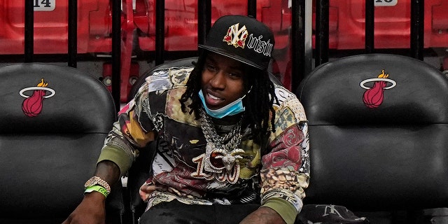 In this April 18, 2021 photo, Rapper Polo G watches during the second half of an NBA basketball game between the Miami Heat and the Brooklyn Nets in Miami.  Officials say rapper Polo G has been arrested in Miami on charges including battery on a police officer, resisting arrest with violence and criminal mischief. Jail records show 22-year-old Taurus Bartlett was booked into jail on Saturday, June 12, 2021.