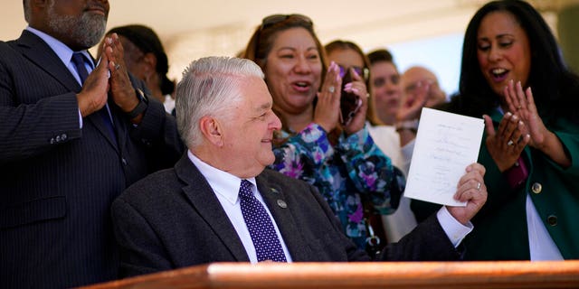 Nevada Democratic Governor Steve Sisolak waves a newly enacted bill on Friday, June 11, 2021 in Las Vegas. The law would make Nevada the first to vote in the 2024 presidential primary elections, although national political parties would have to agree to changes in the timing or states parties could risk losing their delegates at presidential nomination conventions. (AP Photo / John Locher)
