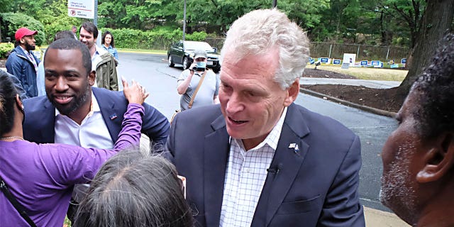 Former Virginia governor Terry McAuliffe, right, and Richmond Mayor Levar Stoney, left, greet McAuliffe supporters during a quick rally outside the Office of the General Registrar, City of Richmond, in Richmond, Va. Friday, June 4, 2021.