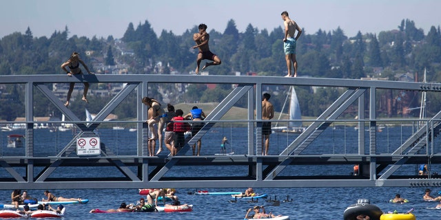 Two people jump from a pedestrian bridge at Lake Union Park into the water during a heat wave hitting the Pacific Northwest, Sunday, June 27, 2021, in Seattle. A day earlier, a record high was set for the day with more record highs expected today and Monday. (AP Photo/John Froschauer)
