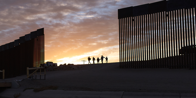 A pair of migrant families from Brazil pass through a gap in the border wall to reach the United States after crossing from Mexico in Yuma, Ariz., Thursday, June 10, 2021, to seek asylum. The families are part of an influx of asylum-seekers entering the U.S. in the Yuma area from South America and other continents. (AP Photo/Eugene Garcia)