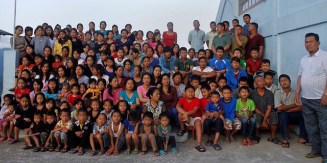 FILE PHOTO: Family members of Ziona (R) poses for group photograph outside their residence in Baktawng village in the northeastern Indian state of Mizoram, October 7, 2011. Ziona has 39 wives, 94 children and 33 grandchildren. REUTERS/Adnan Abidi